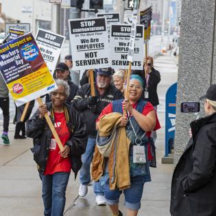 APWU members march down a street holding rally signs