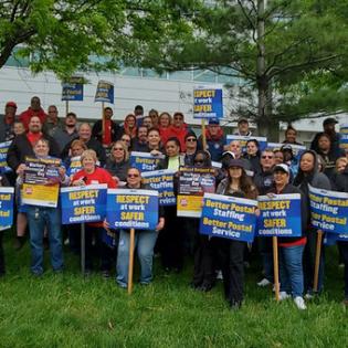 a group of workers hold rally signs on a lawn in Philadelphia