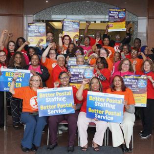 a group of union members from different unions pose with apwu rally signs