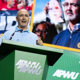 UAW President Shawn Fain speaks at APWU podium during the convention