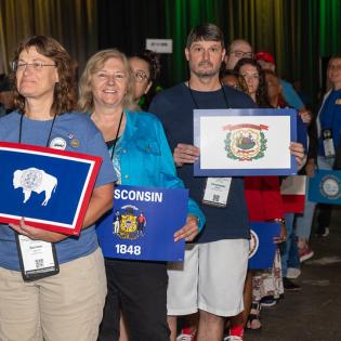 Delegates holding posters that represent their states, here it is New York, walk across the stage