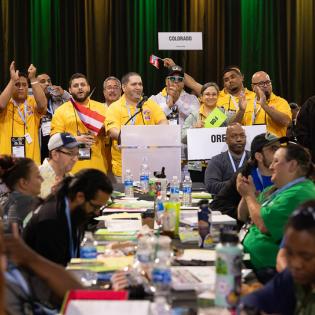 APWU Members in yellow shirts cheer holding a Puerto Rico flag