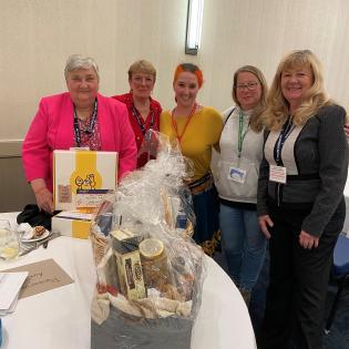 4 women standing in front of items for a raffle. 